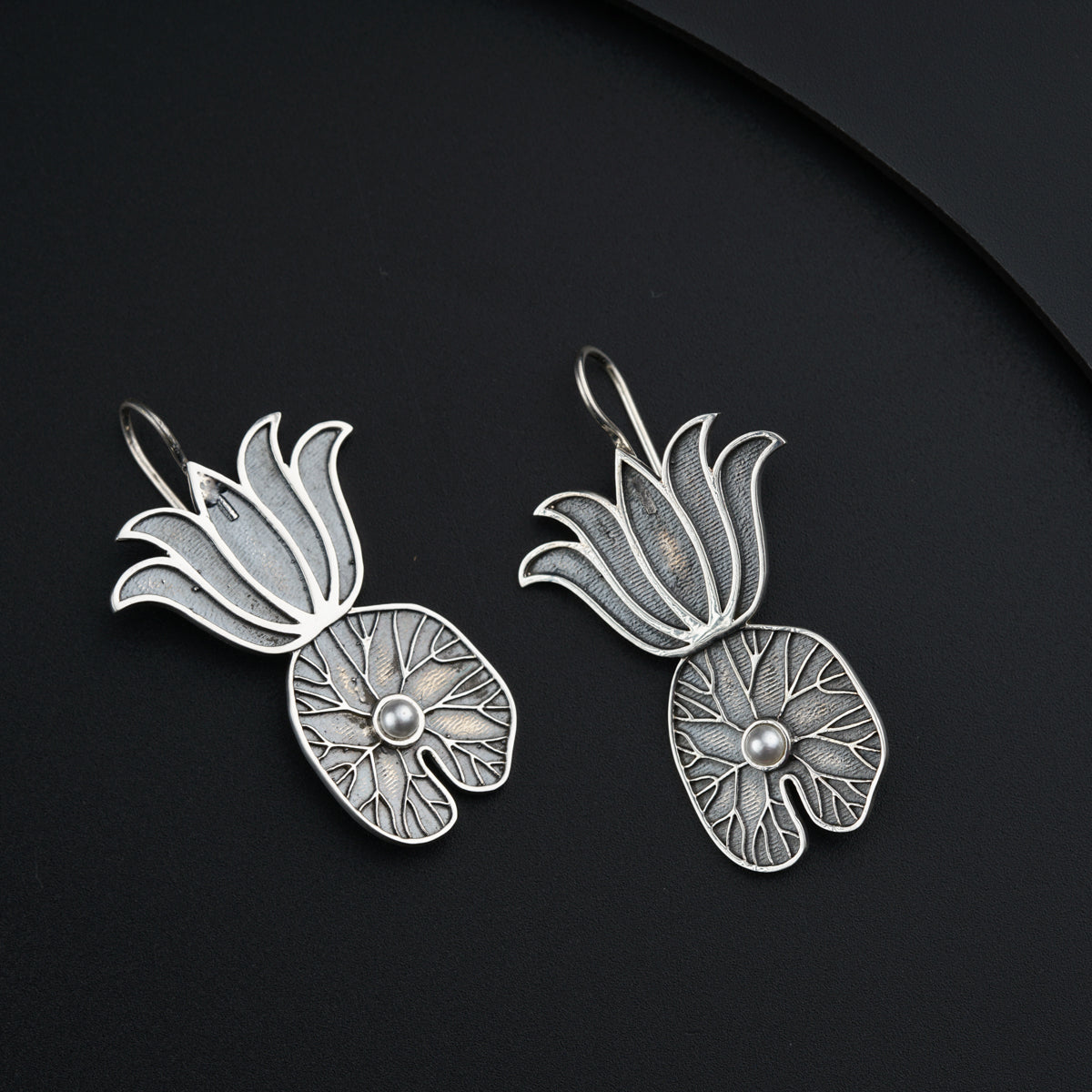a pair of silver earrings on a black surface