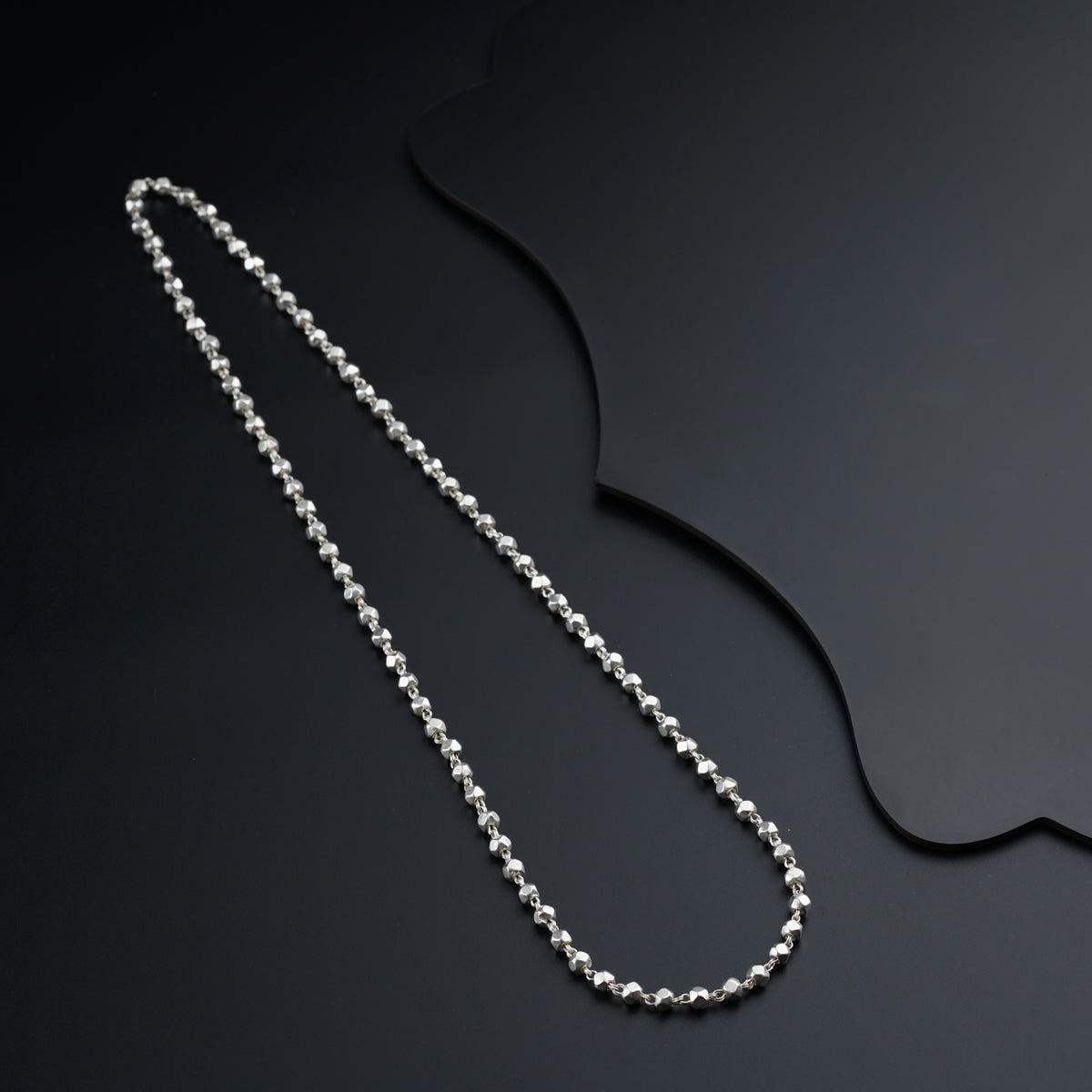 a silver ball chain on a black surface