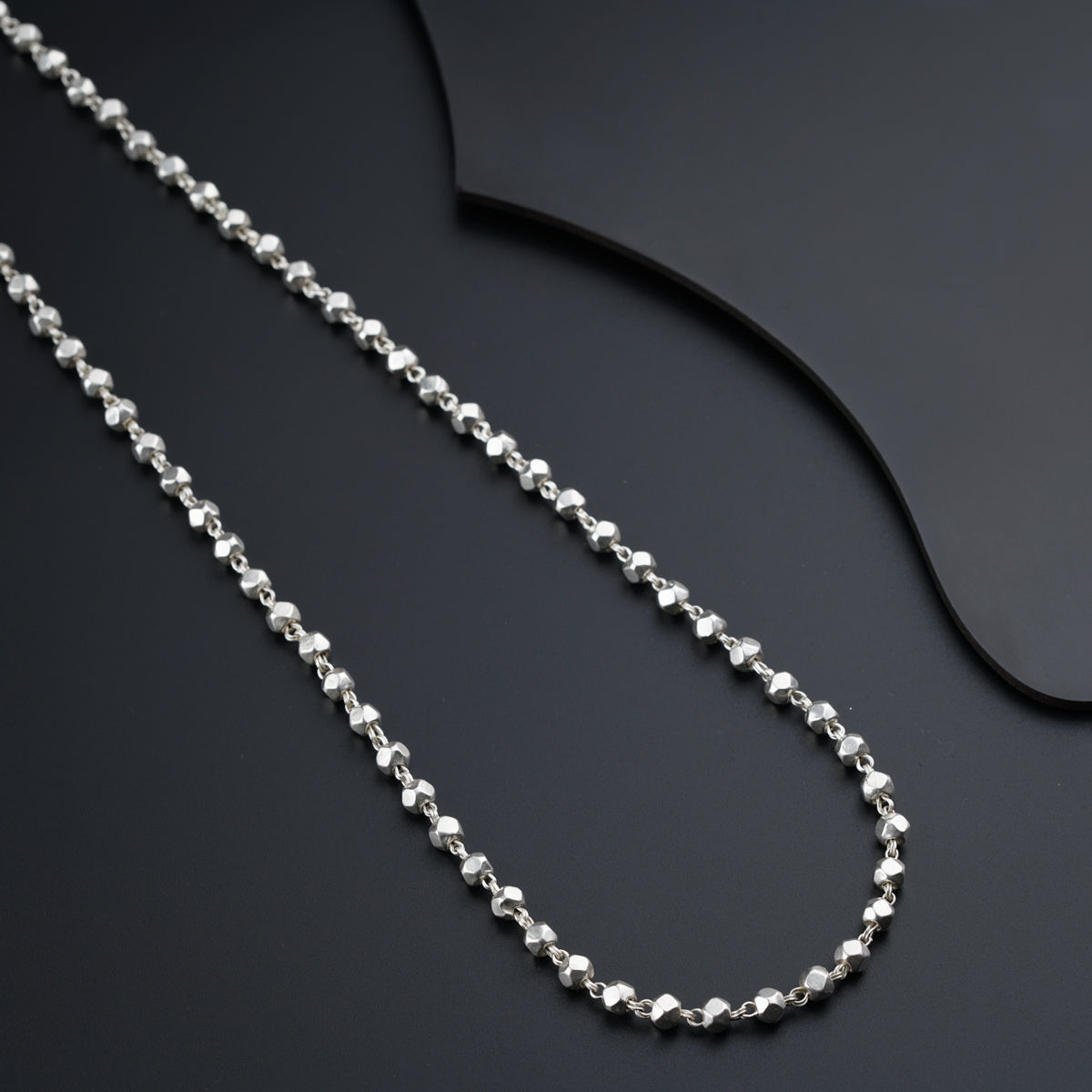 a silver chain on a black surface