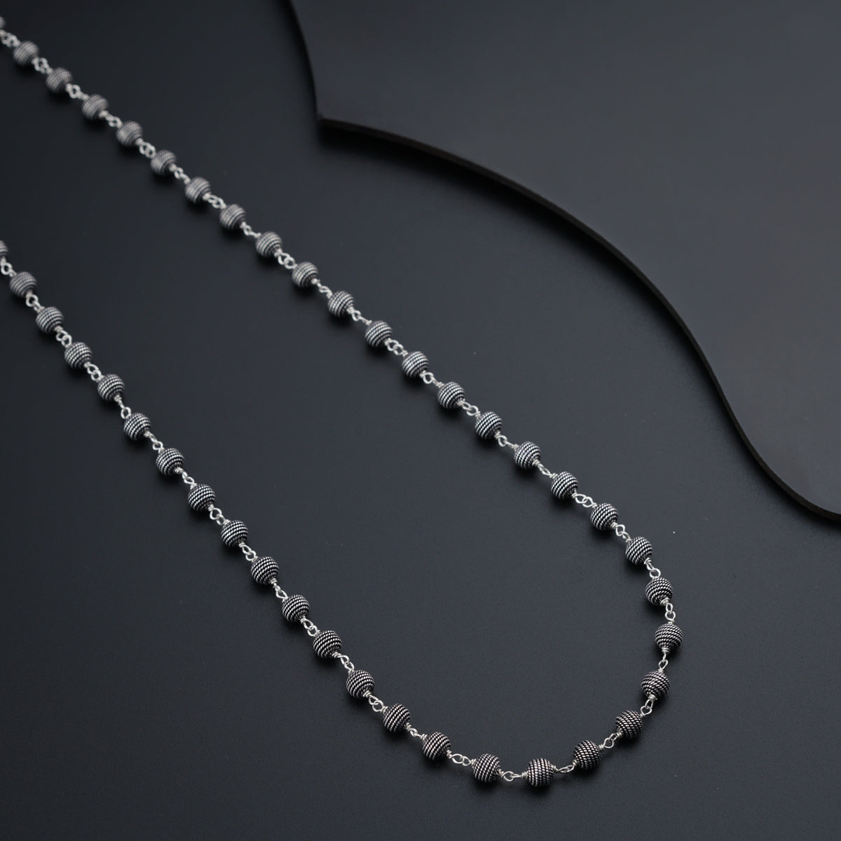 a chain of silver beads on a black surface