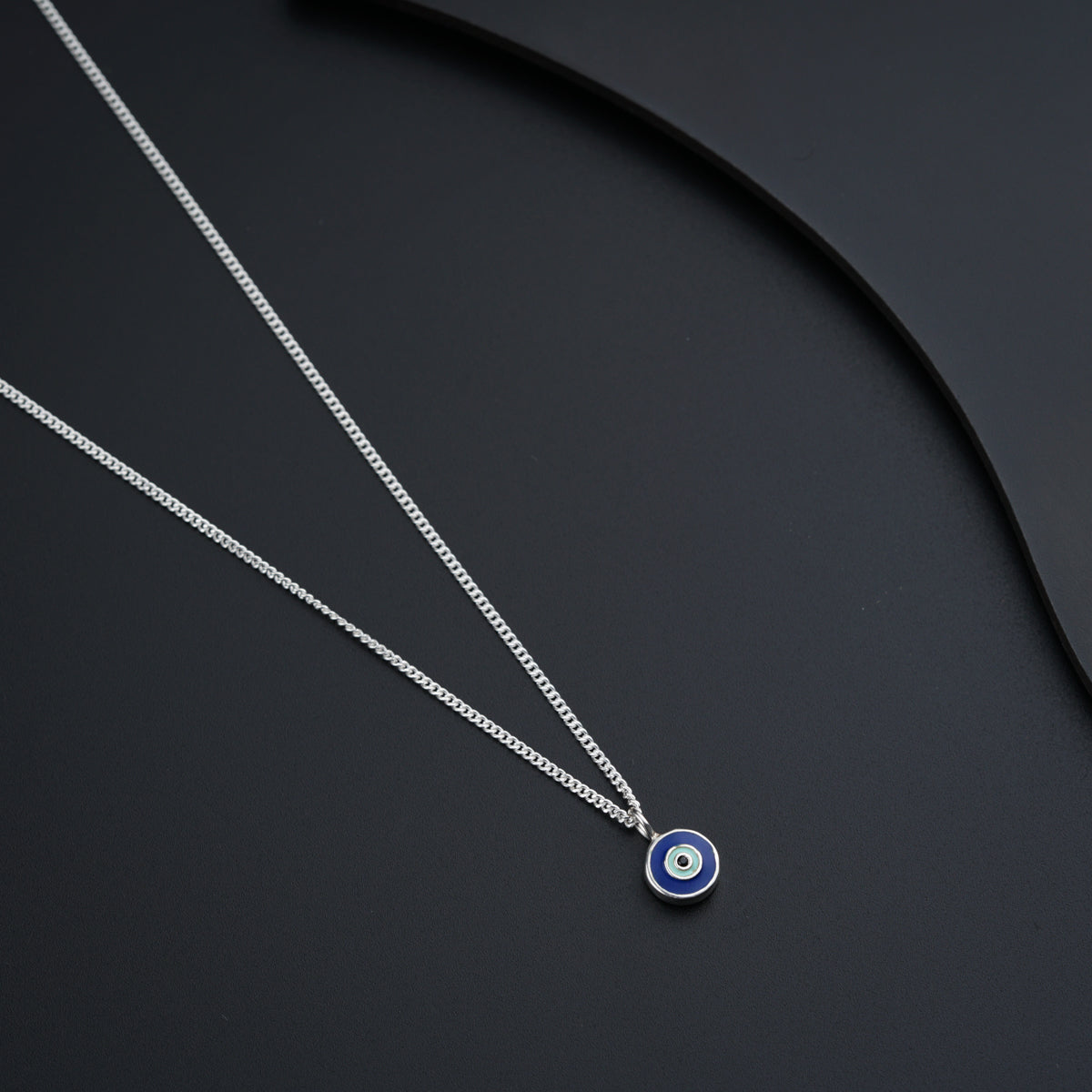 a blue evil eye necklace on a black surface