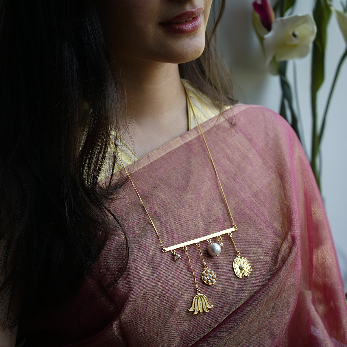 a woman wearing a pink sari and a gold necklace