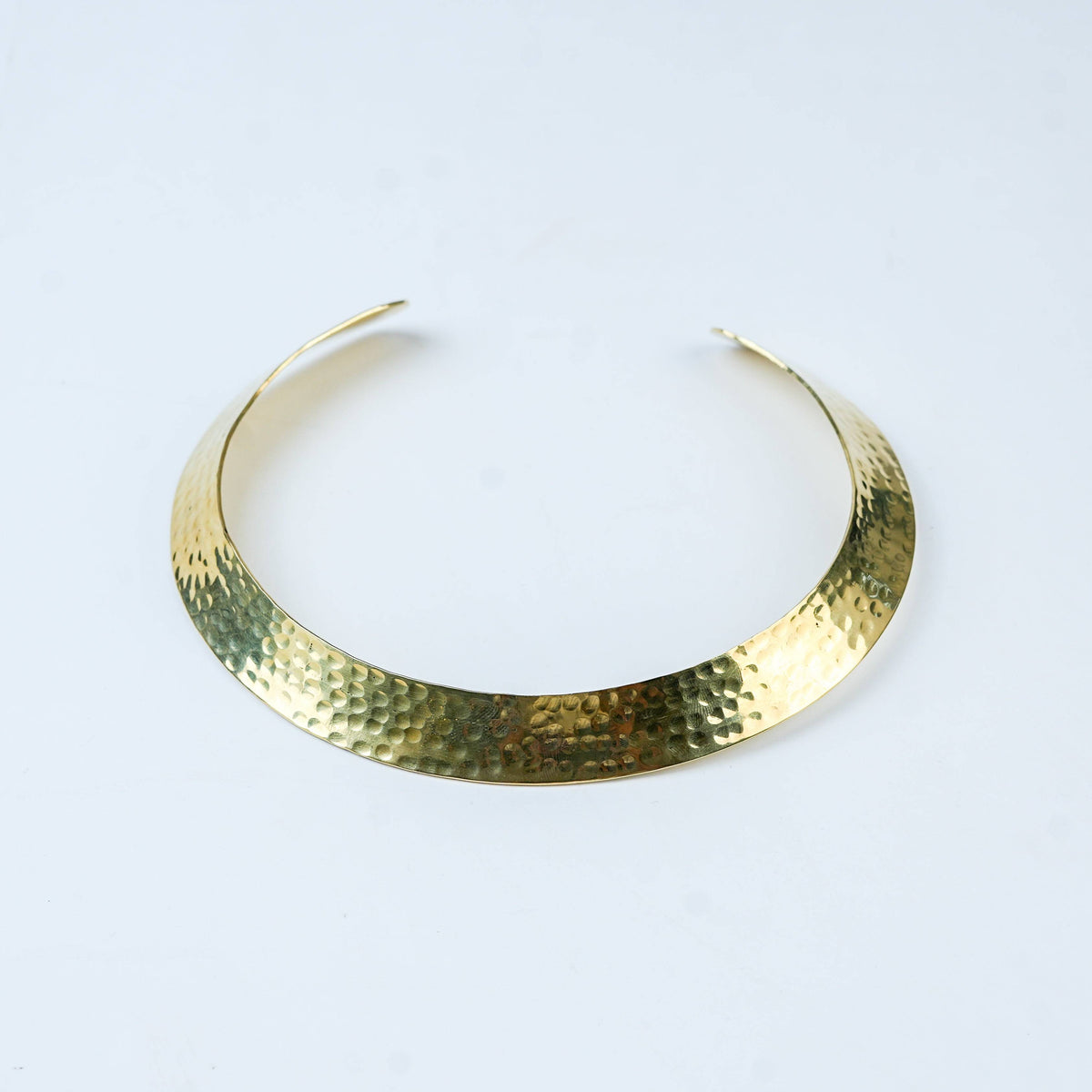 Detailed view of a brass fashion necklace highlighting intricate motifs, textured surface, and refined brass finish