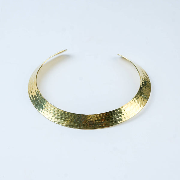 Detailed view of a brass fashion necklace highlighting intricate motifs, textured surface, and refined brass finish