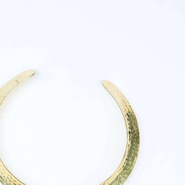 Angled view of a brass fashion necklace highlighting its unique silhouette, structure, and polished brass finish