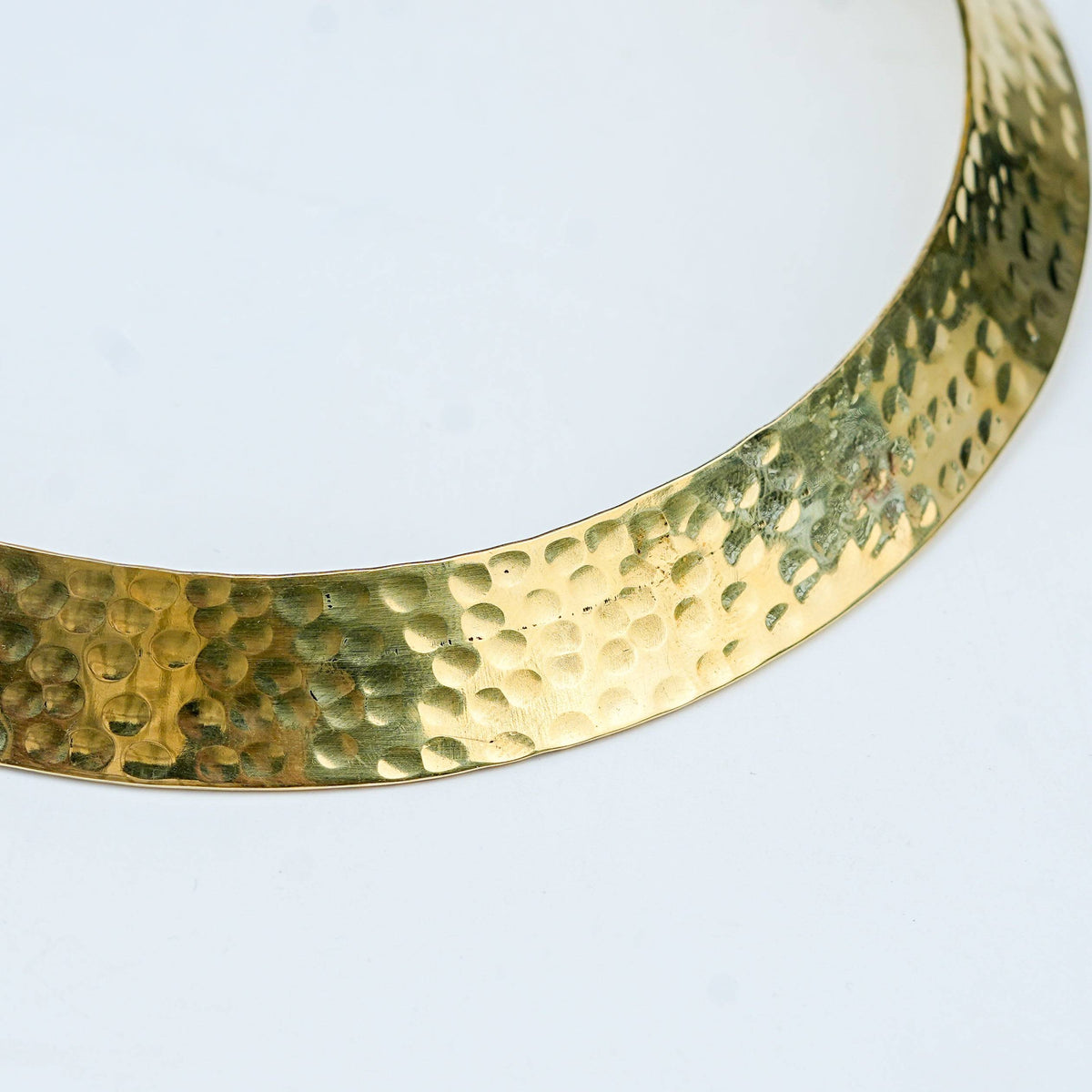 Close-up of a brass fashion necklace showcasing intricate detailing, textured elements, and fine craftsmanship