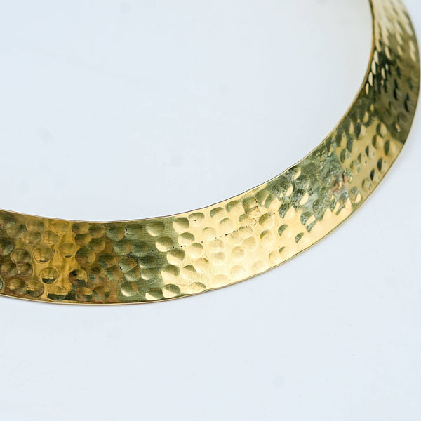 Close-up of a brass fashion necklace showcasing intricate detailing, textured elements, and fine craftsmanship