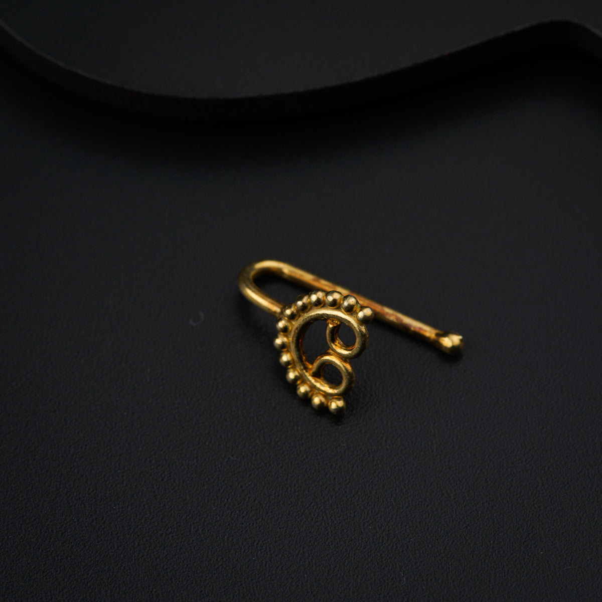 a pair of gold earrings sitting on top of a black surface
