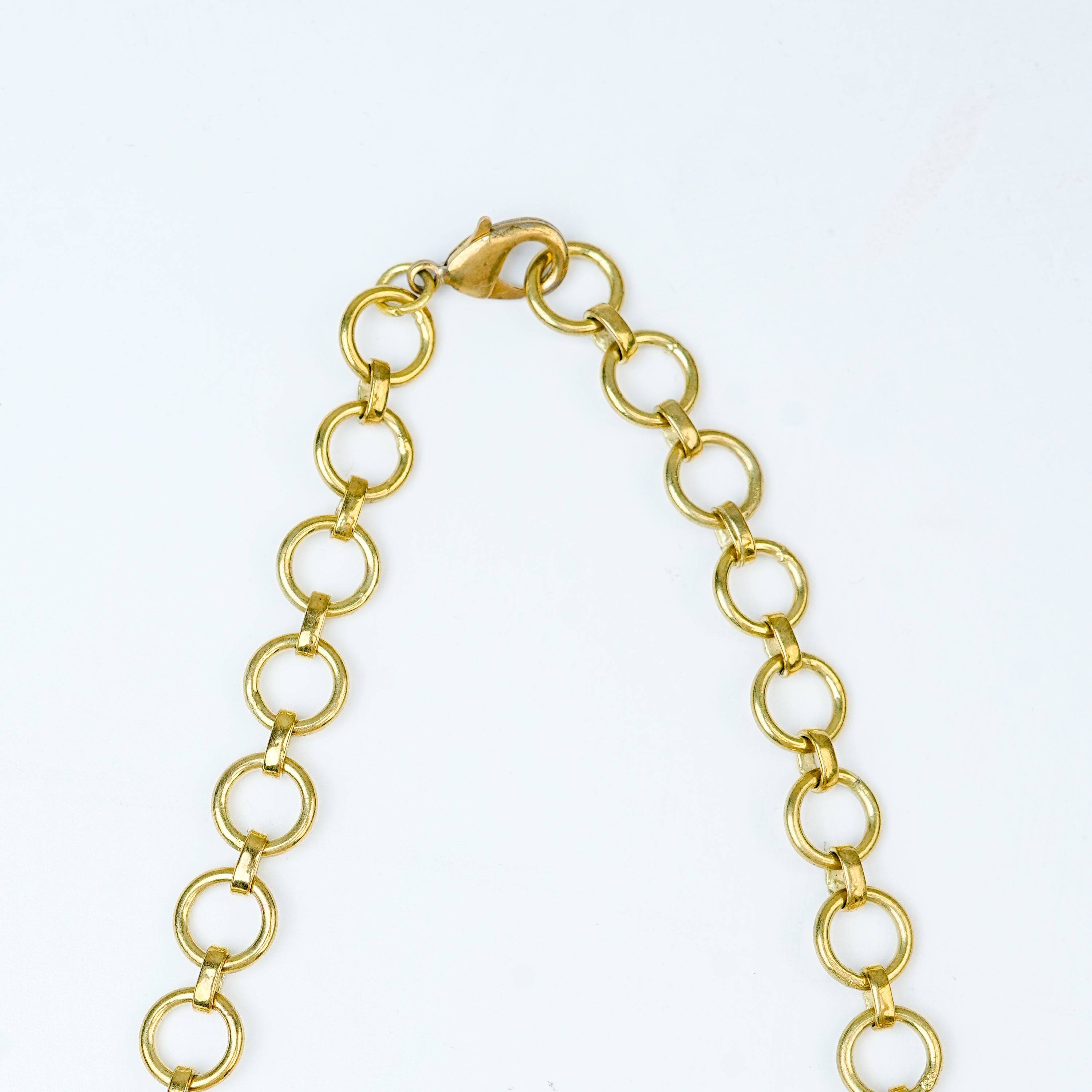 Angled view of a brass fashion necklace highlighting its unique silhouette, structure, and polished brass finish