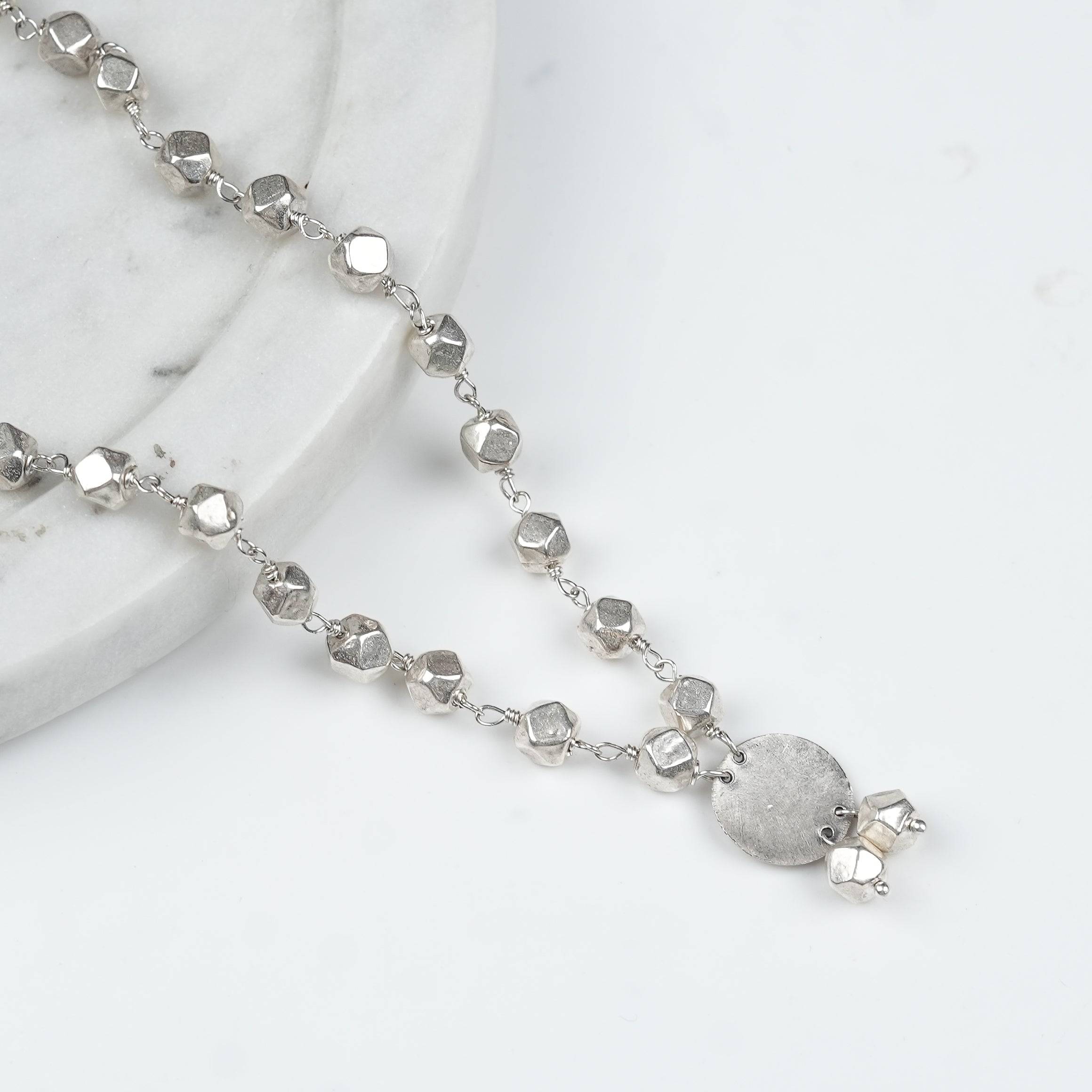 Angled view of Ashtapailu Necklace with Plain Coin Pendant (Small) in 92.5 sterling silver with a simple coin pendant