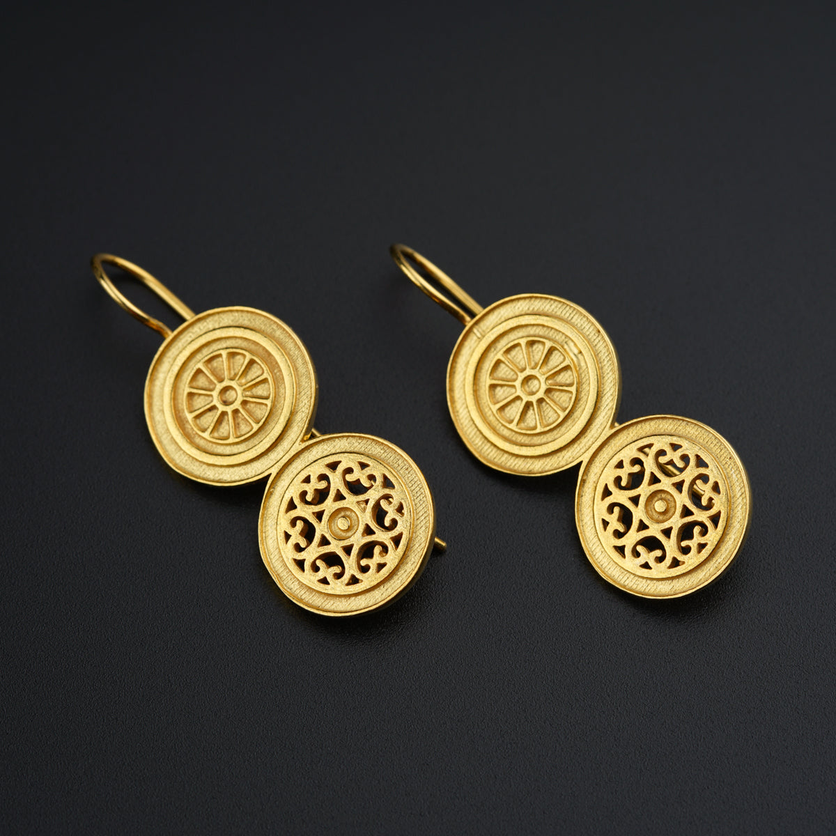 a pair of gold earrings on a black surface