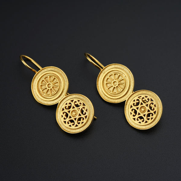 a pair of gold earrings on a black surface