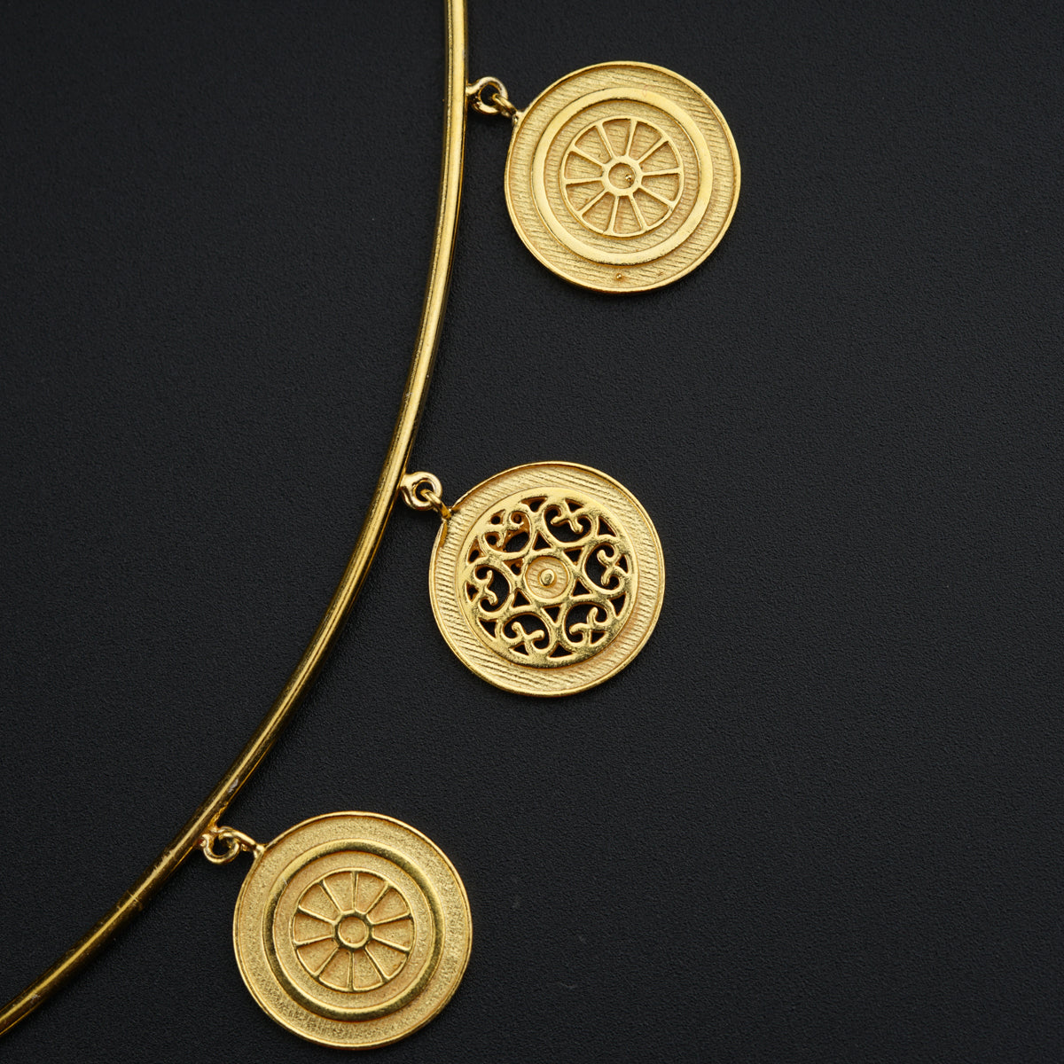 a close up of a gold necklace on a black surface