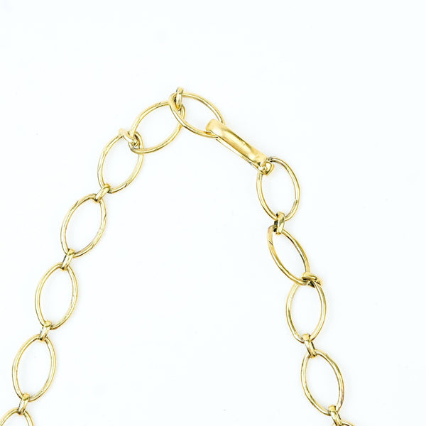 Angled view of a brass fashion necklace highlighting its unique silhouette, structure, and polished brass finish