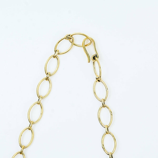 Angled view of a brass fashion necklace highlighting its unique silhouette, structure, and polished brass finish