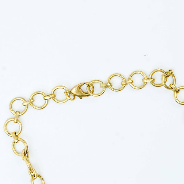 Angled view of a brass fashion necklace highlighting its unique silhouette, structure, and polished brass finish