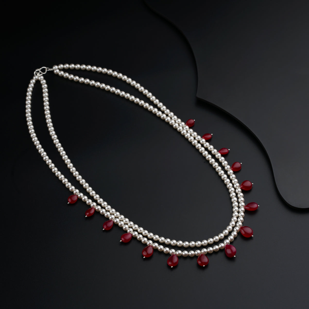 a necklace with pearls and garnets on a black surface