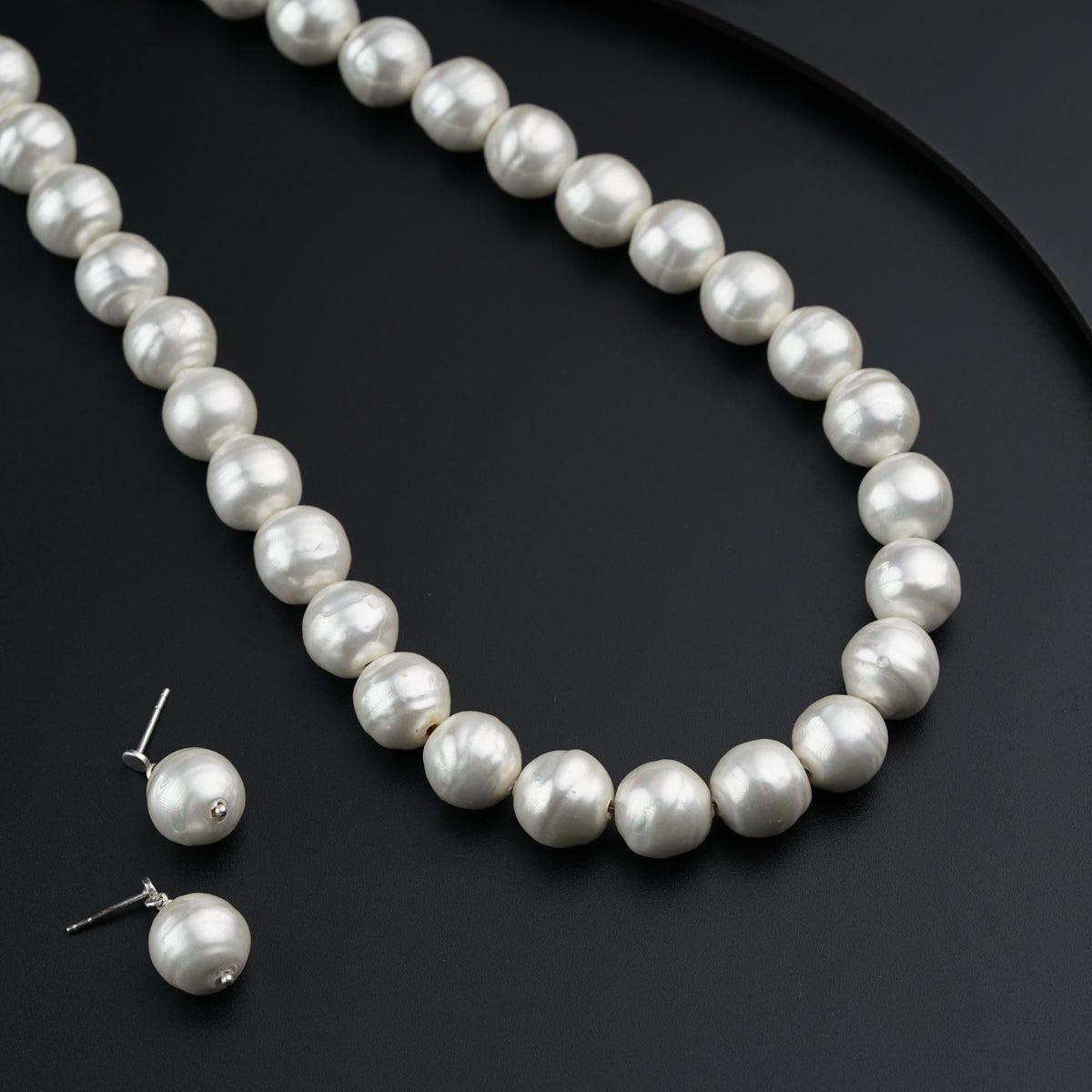 a white pearl necklace and earrings on a black surface
