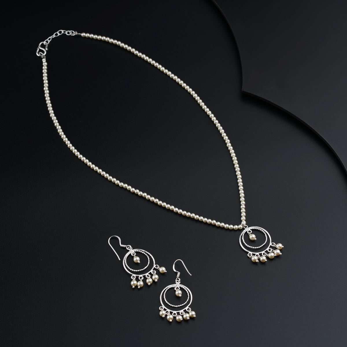 a necklace and earrings on a black surface