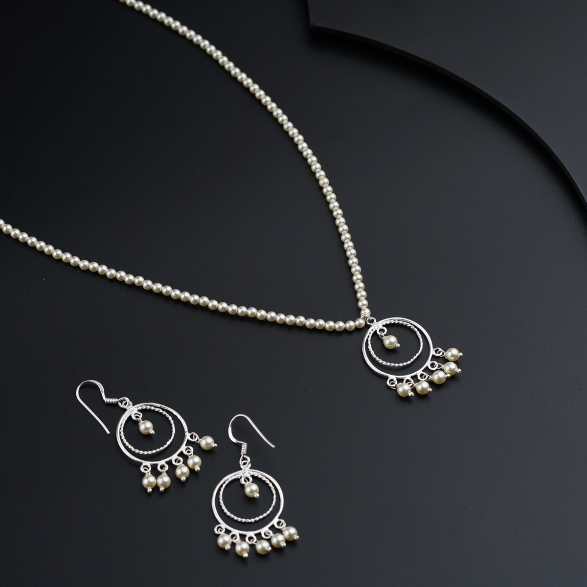 a necklace and earrings on a black surface