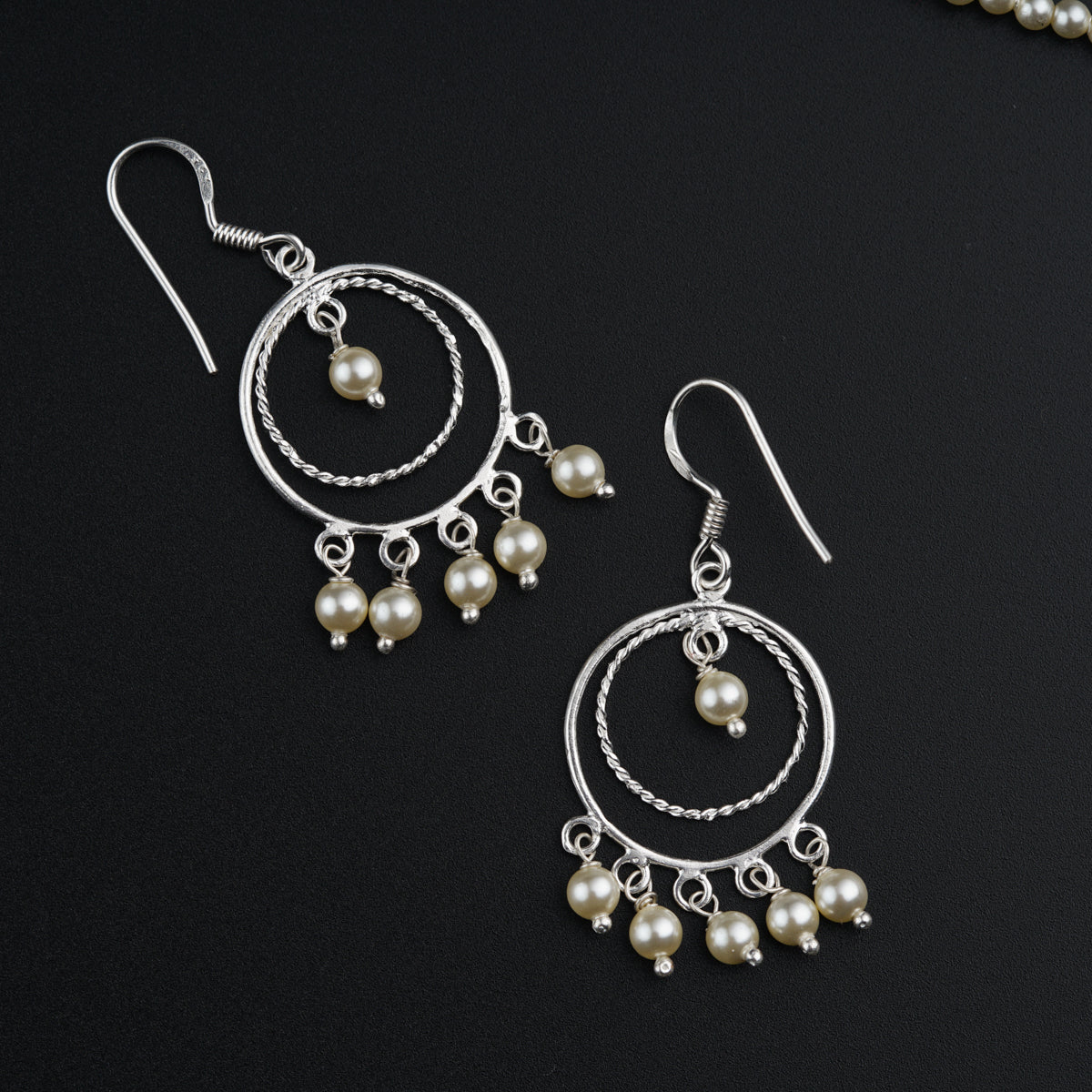 a pair of earrings with pearls hanging from them