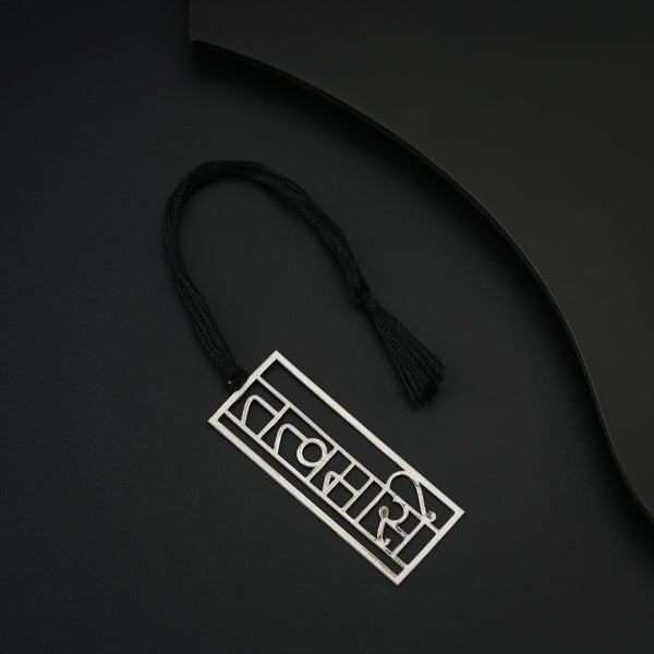 Silver gift set tag with black tassel on black background