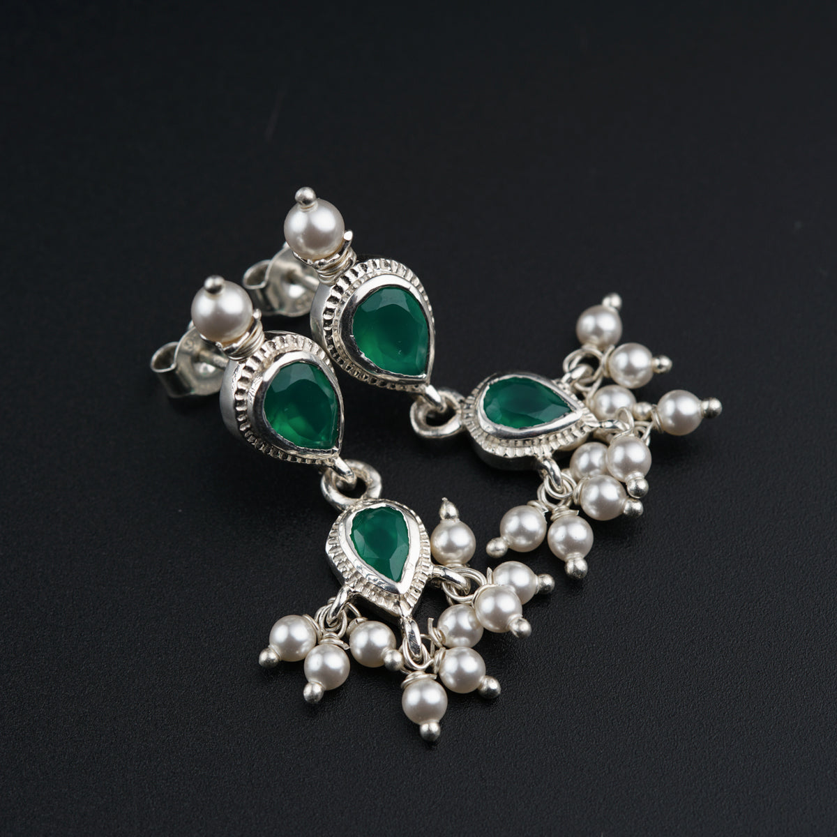 a pair of green and white earrings on a black surface