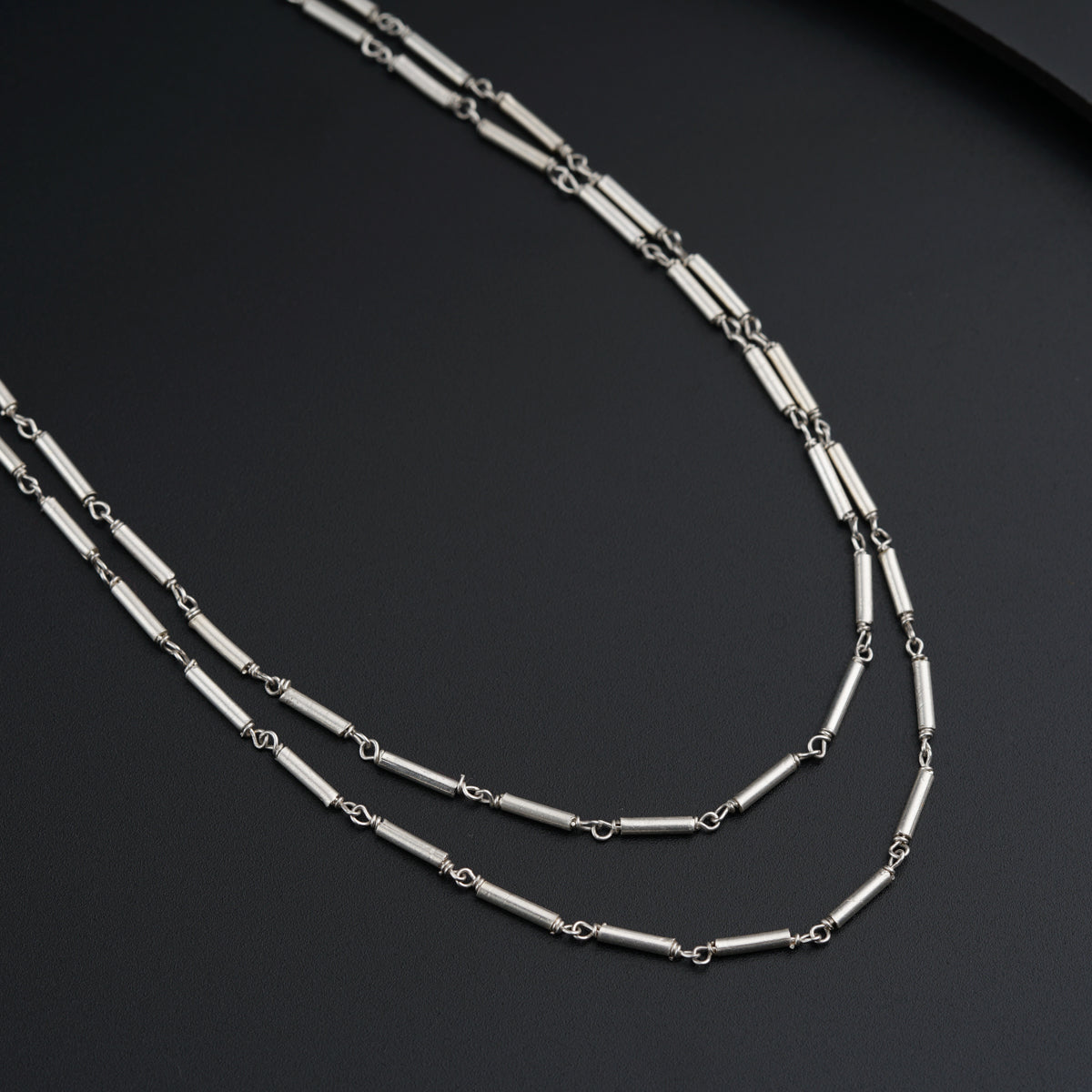 a long silver chain with two links on a black surface