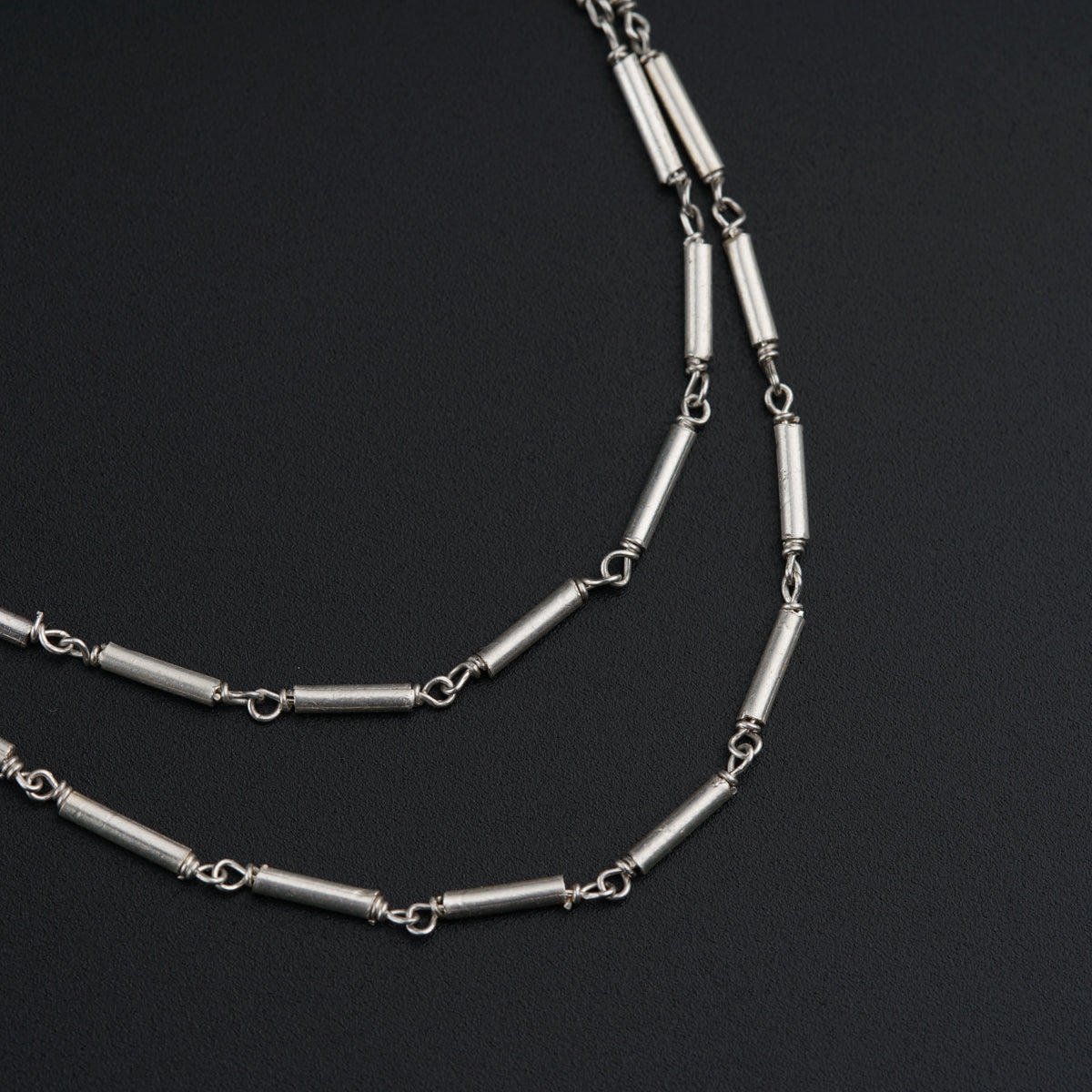 a long silver chain with links on a black surface