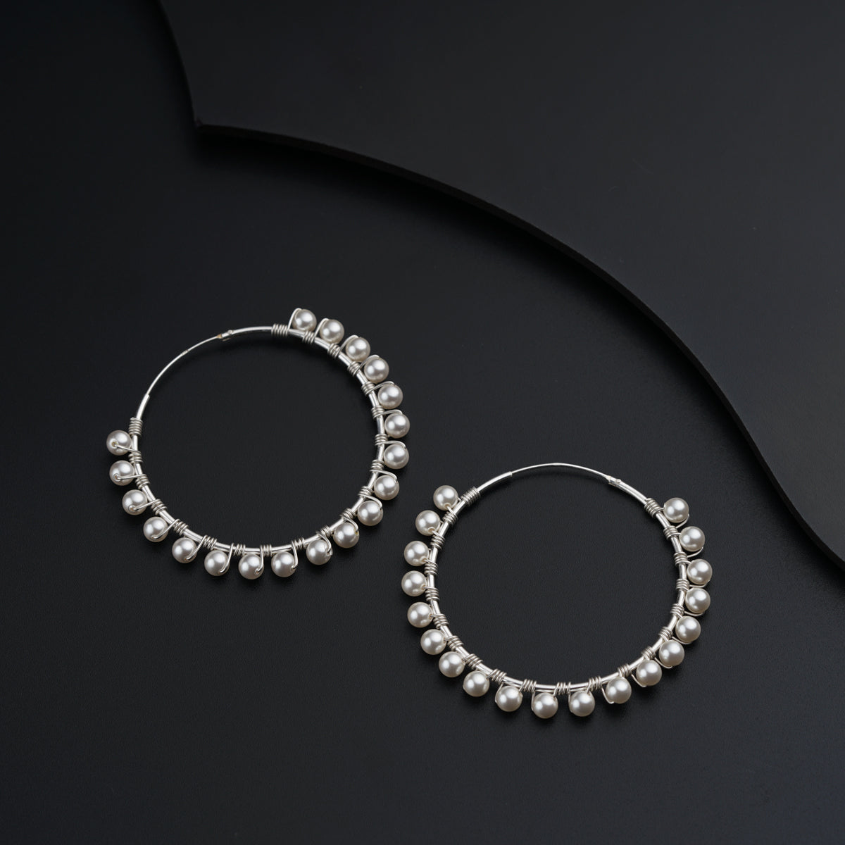 a pair of hoop earrings with pearls on a black background