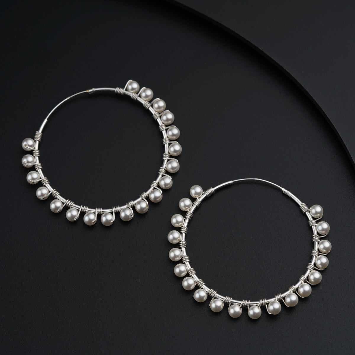 a pair of hoop earrings with pearls on a black background