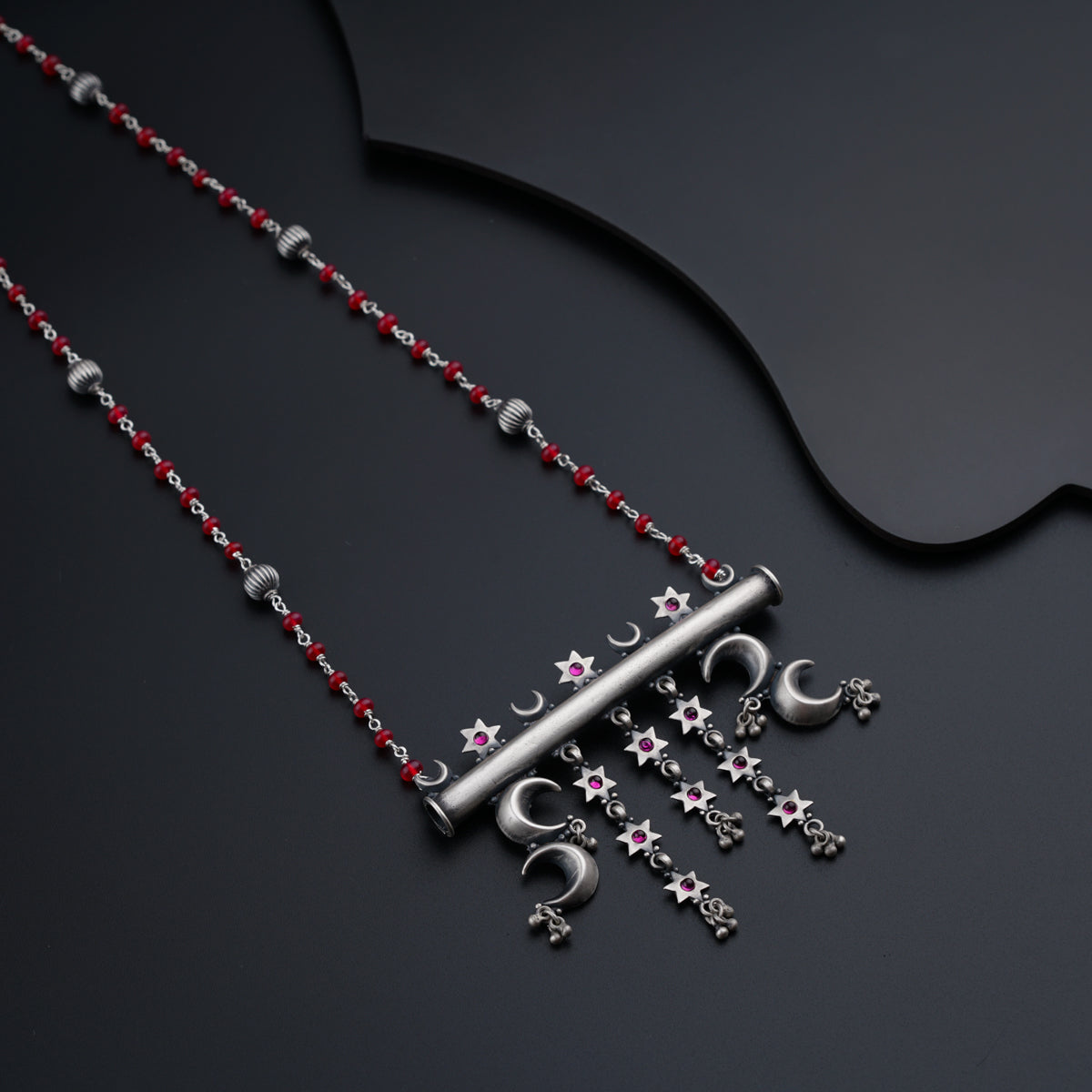 a silver necklace with red beads and stars