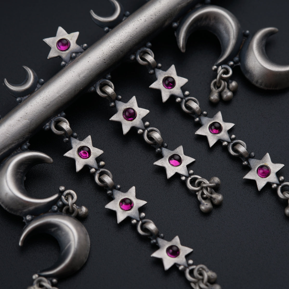 a close up of a chain with stars and moon charms