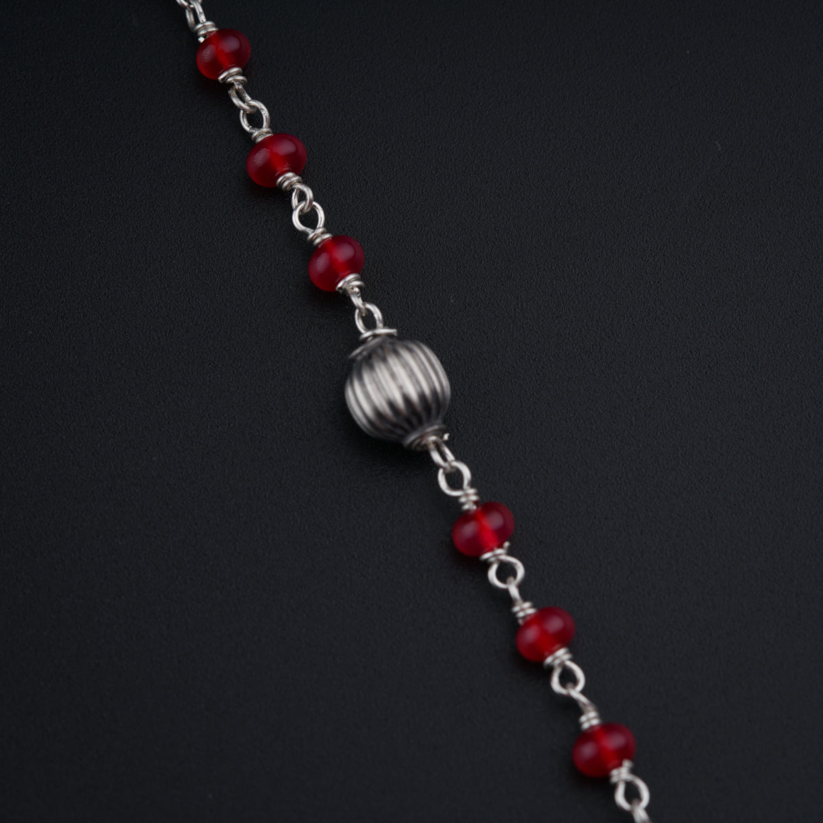 a red beaded bracelet on a black surface