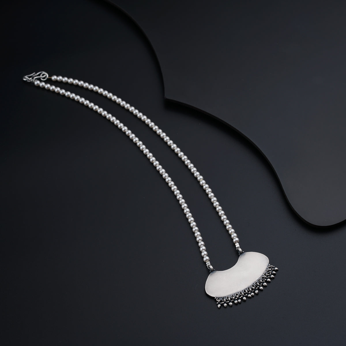 a necklace with a white heart on a black background