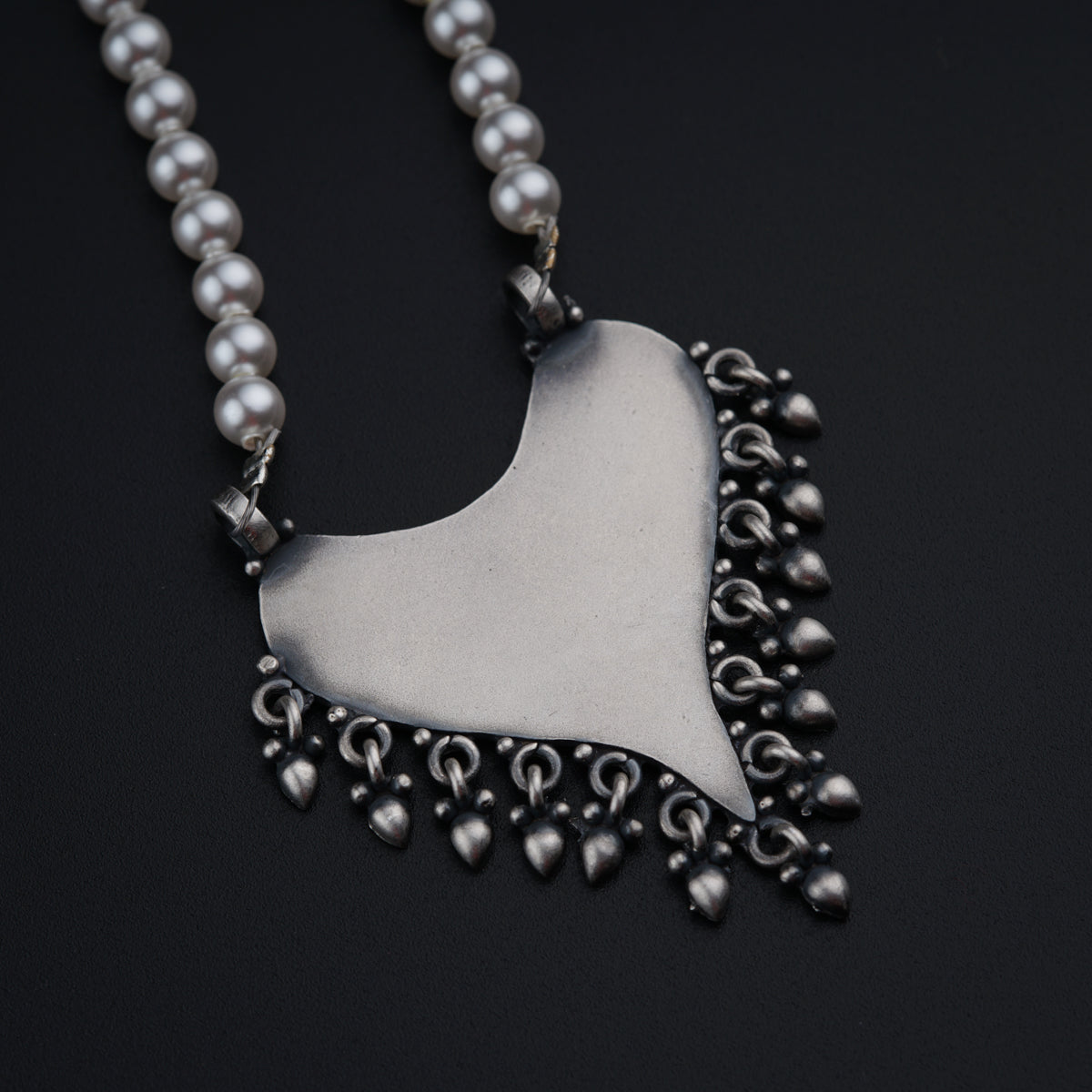 a necklace with a heart shaped pendant on a black background
