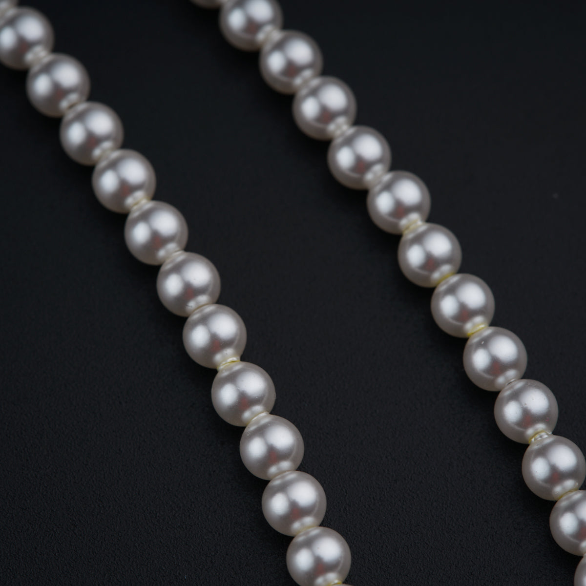 a long strand of white pearls on a black surface