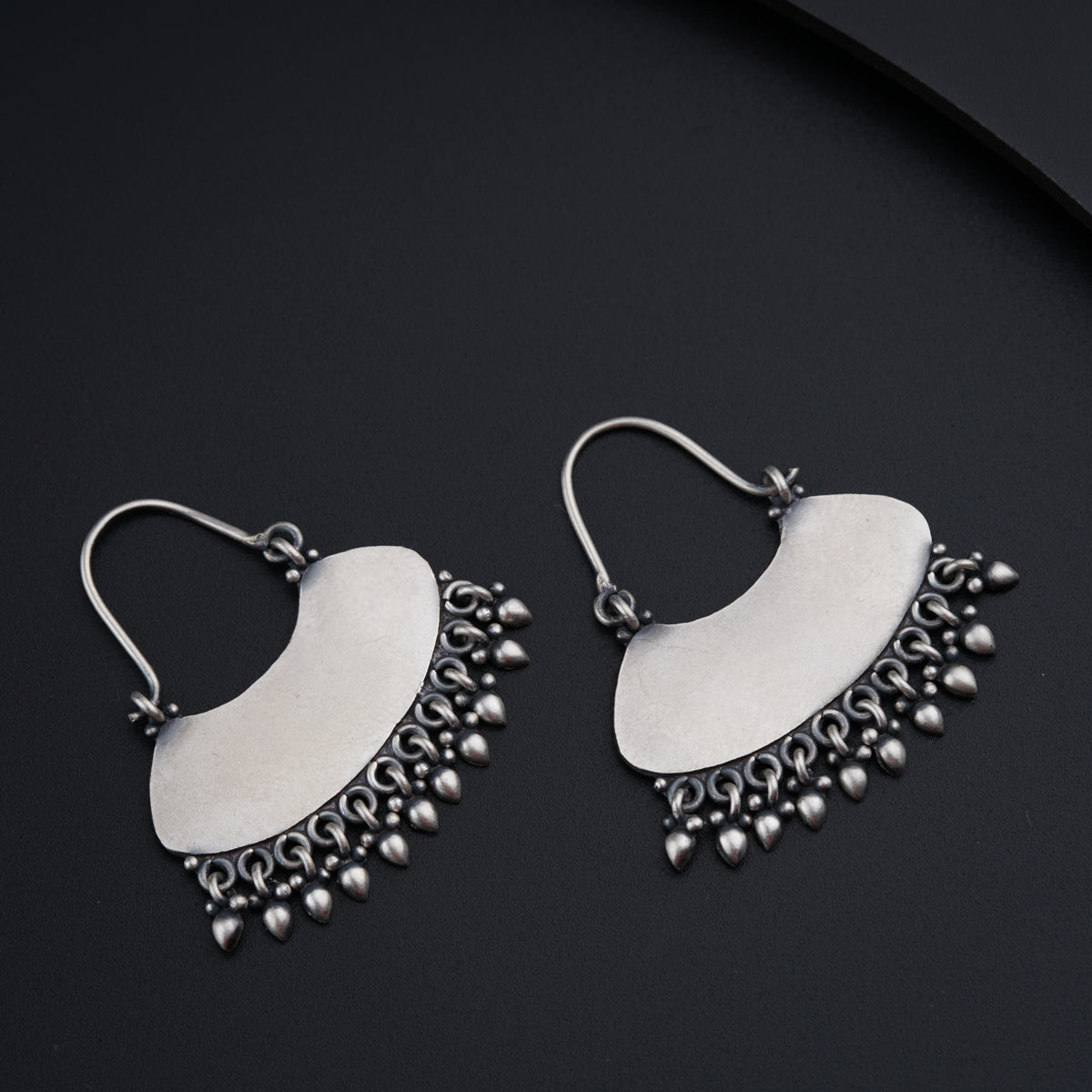a pair of silver earrings on a black surface