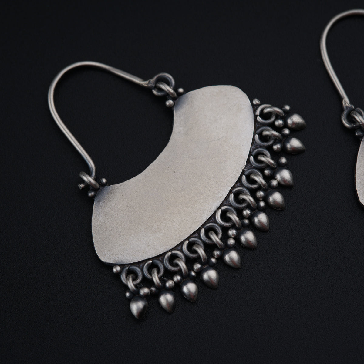 a pair of silver earrings on a black background