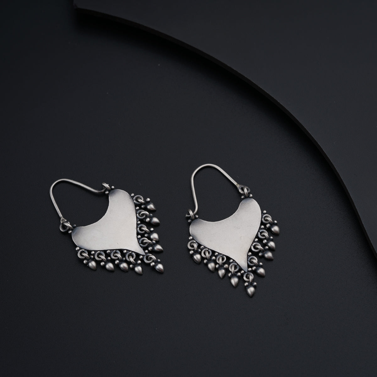 a pair of white and silver earrings on a black surface