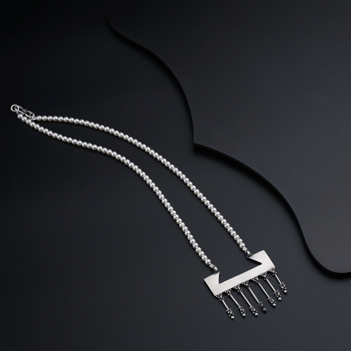a necklace with a comb on a black background