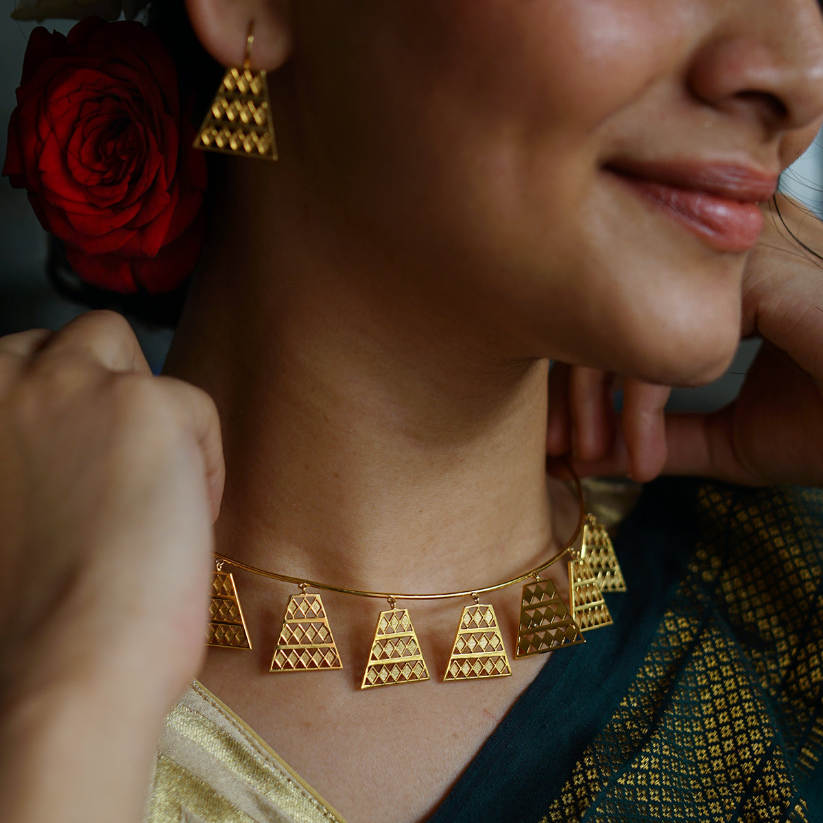 a woman wearing a gold necklace and matching earrings