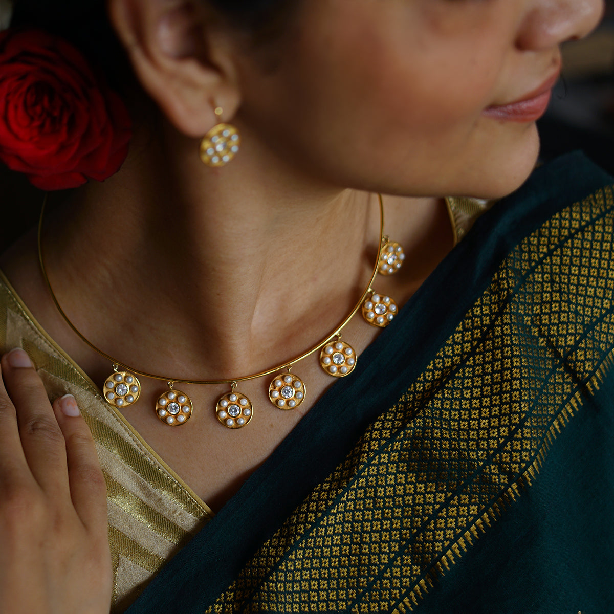 a woman wearing a gold necklace and matching earrings