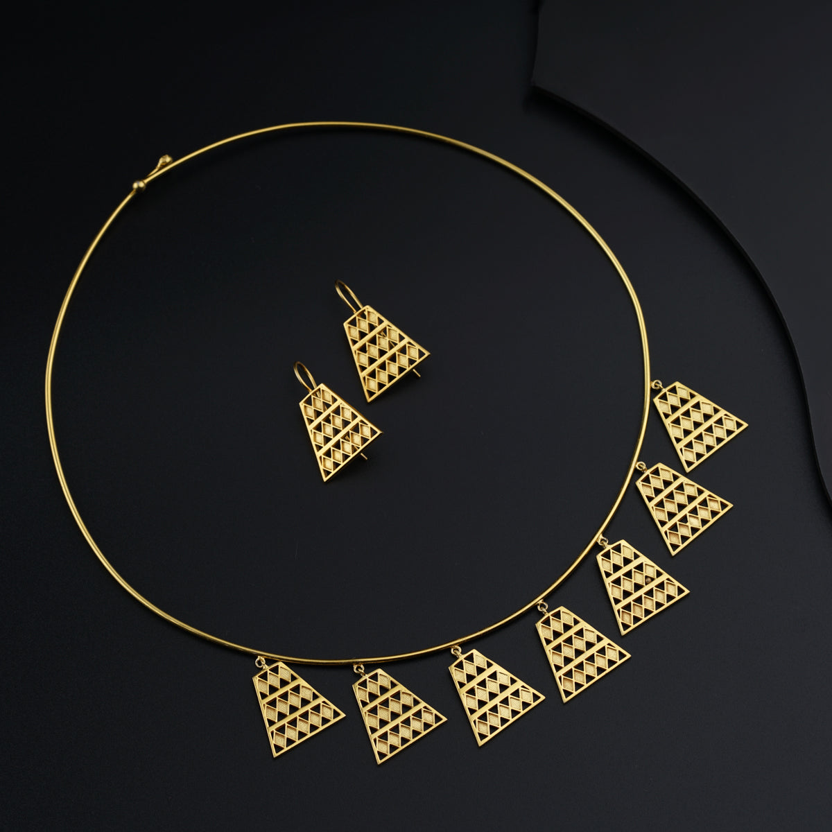 a gold necklace and matching earrings on a black background