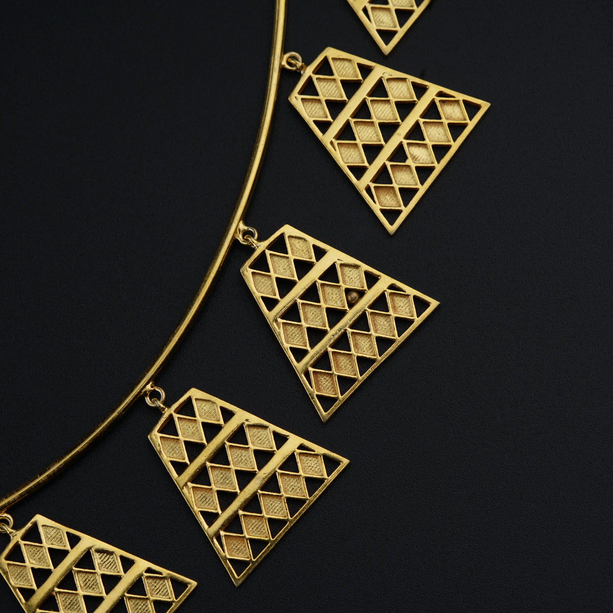 a close up of a gold necklace on a black surface