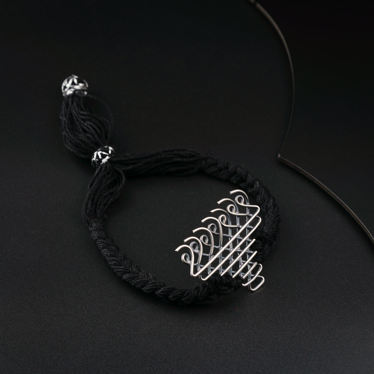 a black string bracelet with a silver bead on it