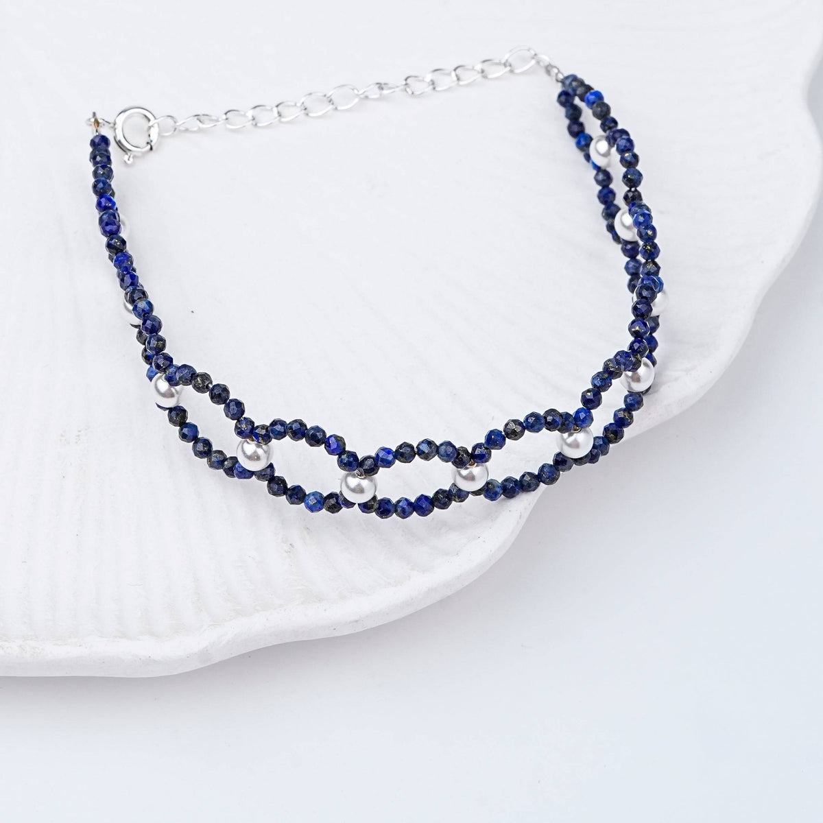 Flat-lay of Lapis Lazuli & Pearl Silver Bracelet with natural lapis lazuli, pearls, and complementary silver jewelry