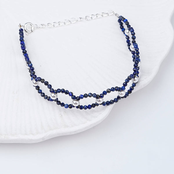 Flat-lay of Lapis Lazuli & Pearl Silver Bracelet with natural lapis lazuli, pearls, and complementary silver jewelry