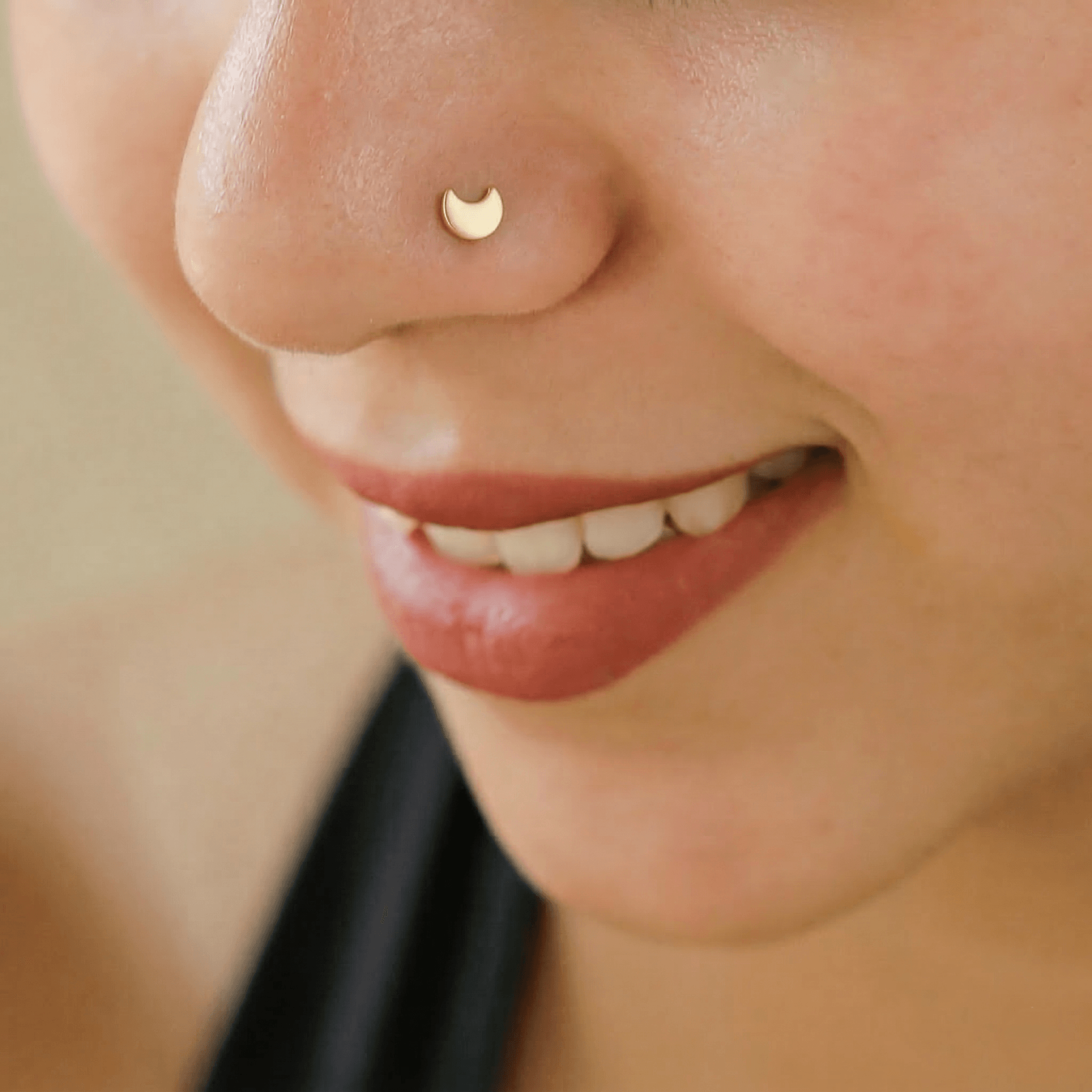Pierced gold-plated crescent moon nose pin on white background