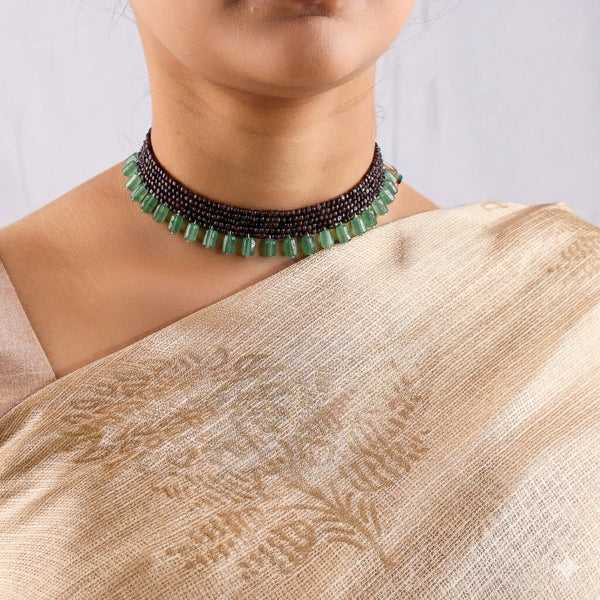 Model wearing garnet and green stone choker necklace with silk saree